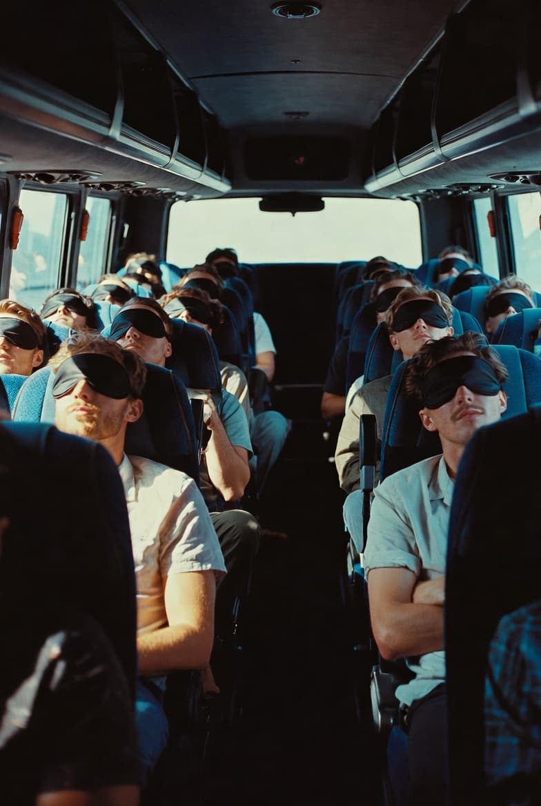 Men wearing blindfolds riding a bus in silence to an unknown retreat location