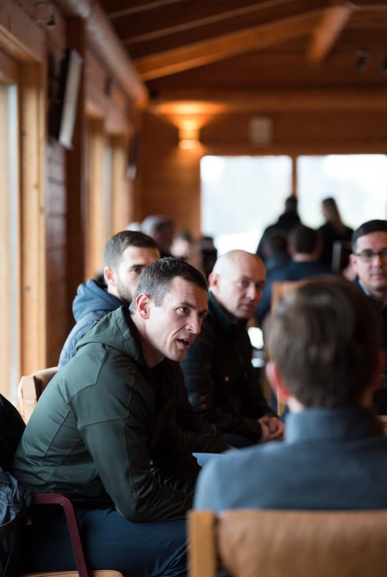 A guided conversation leader sharing his story with men seated in a lodge